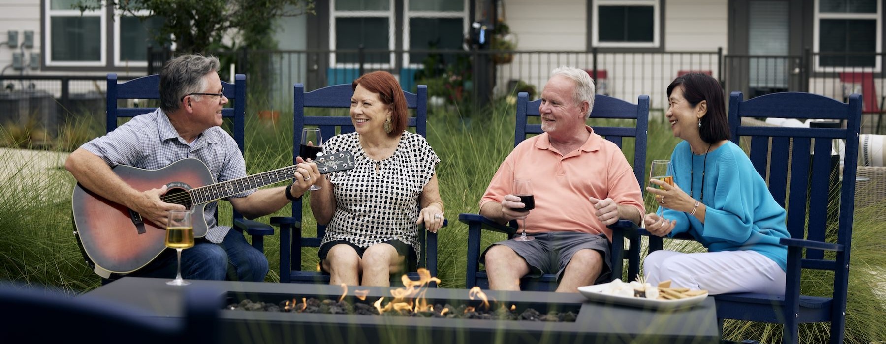 people sitting around fire and a man playing a guitar